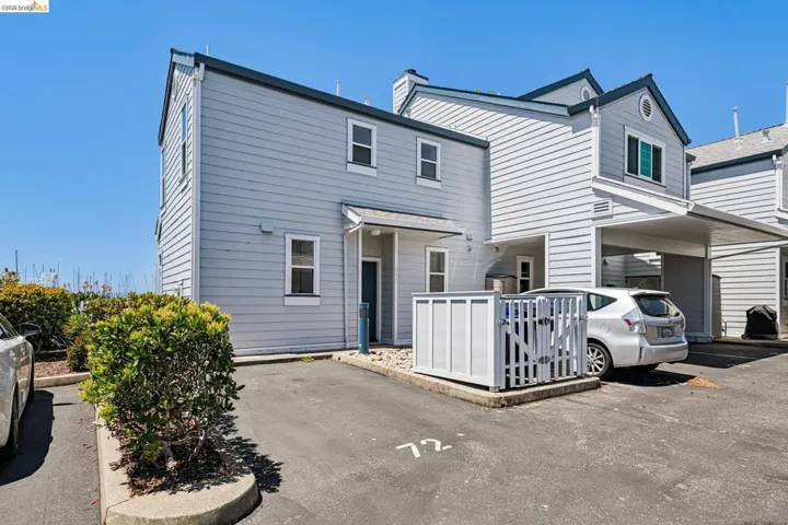 Exterior featuring light gray siding with dark trim, multiple windows, and a covered entry