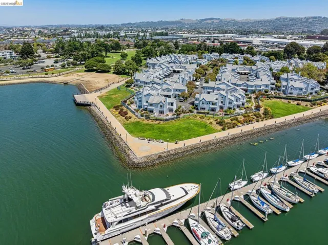 Waterfront community featuring a marina with docked boats, a paved promenade, and mature landscaping