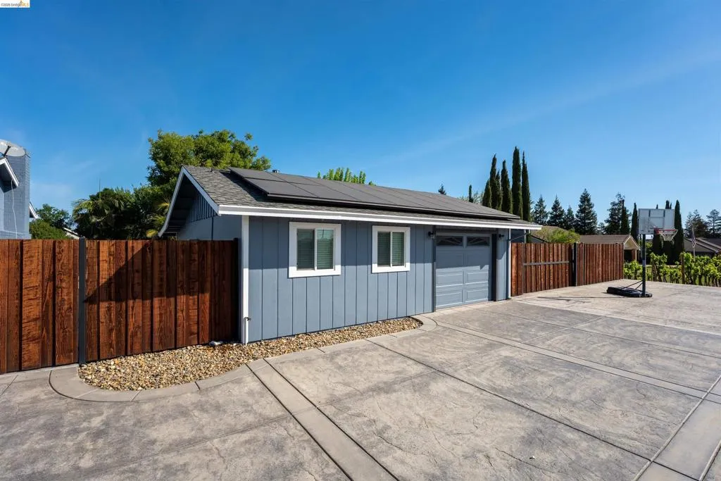 Detached ADU with a garage door, two windows with white trim, and solar panels on the roof