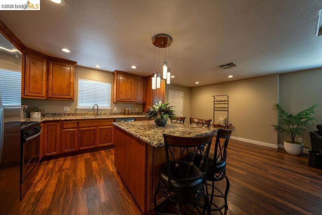 Kitchen featuring wood-finish flooring, recessed lighting, and a center island with a granite-style countertop