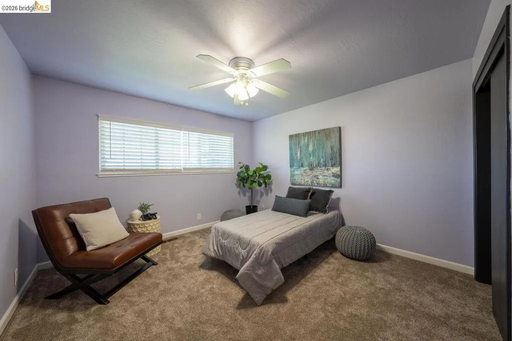 Spacious room with light lavender walls, plush carpet, and a ceiling fan with integrated lighting
