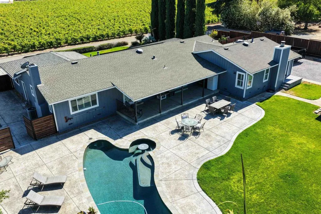 Expansive outdoor living area featuring a freeform swimming pool, extensive stamped concrete patio, covered patio space, and a manicured lawn