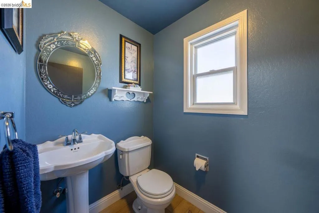 Pedestal sink with chrome fixtures and an ornate framed mirror