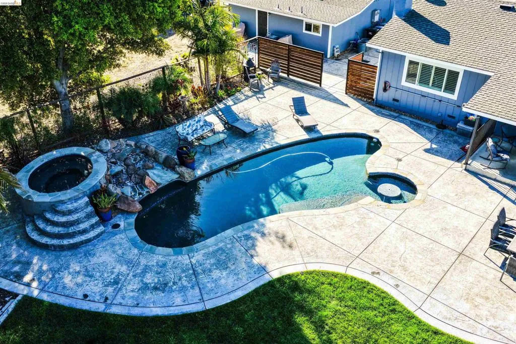 Backyard oasis featuring an irregular-shaped swimming pool, integrated spa, and a stone-clad fire pit with tiered steps