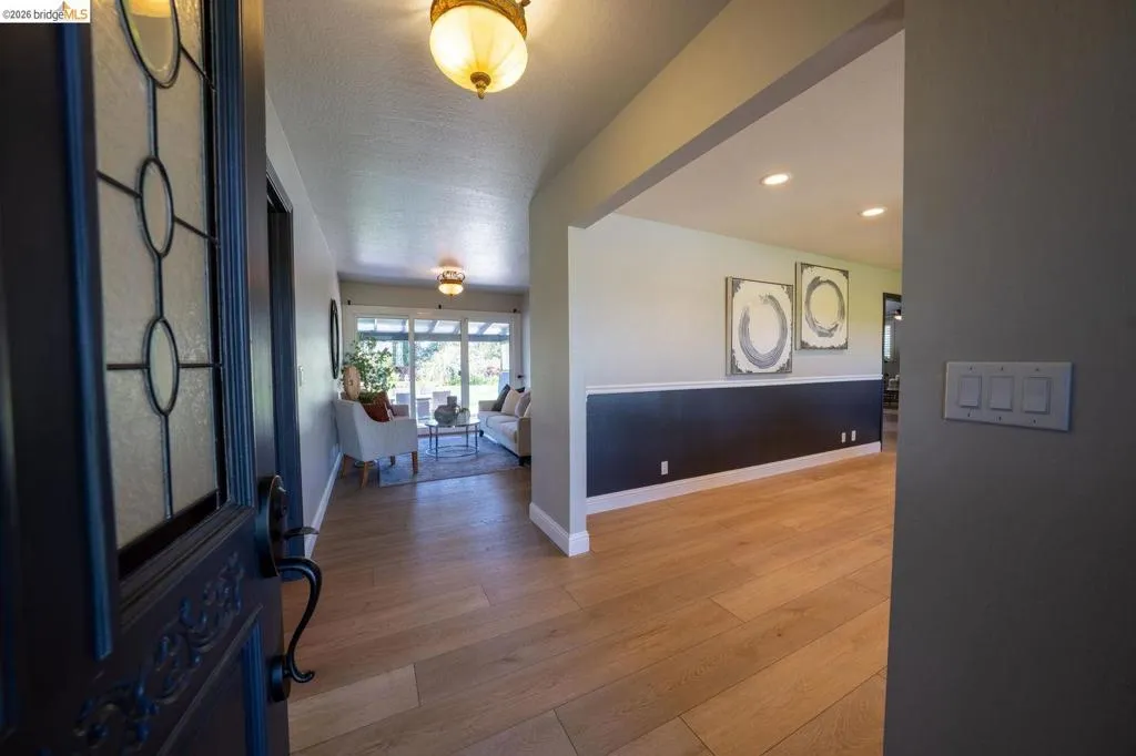 Entrance hall featuring a decorative glass paneled door, light wood-finish flooring, recessed lighting, and a chair rail with contrasting wall tones