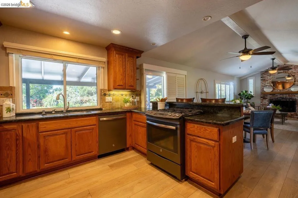 Kitchen featuring wood cabinetry, dark countertops, tile backsplash, and stainless steel appliances