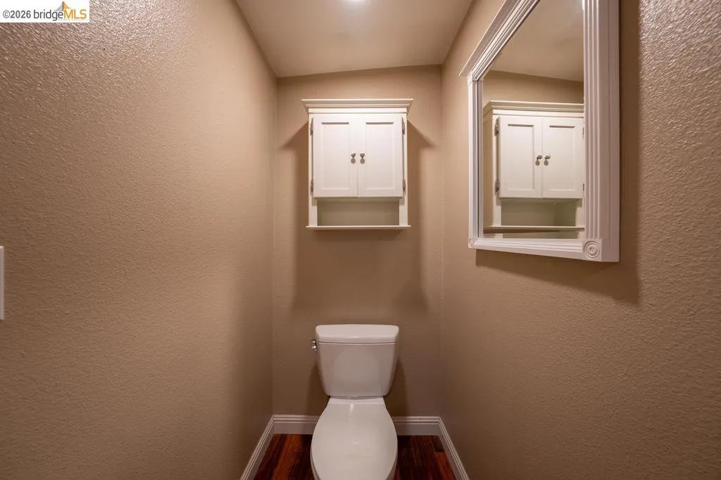 Compact restroom featuring wood-finish flooring, a white toilet, and a recessed ceiling light