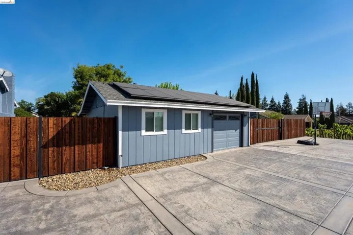Detached ADU with a garage door, two windows with white trim, and solar panels on the roof