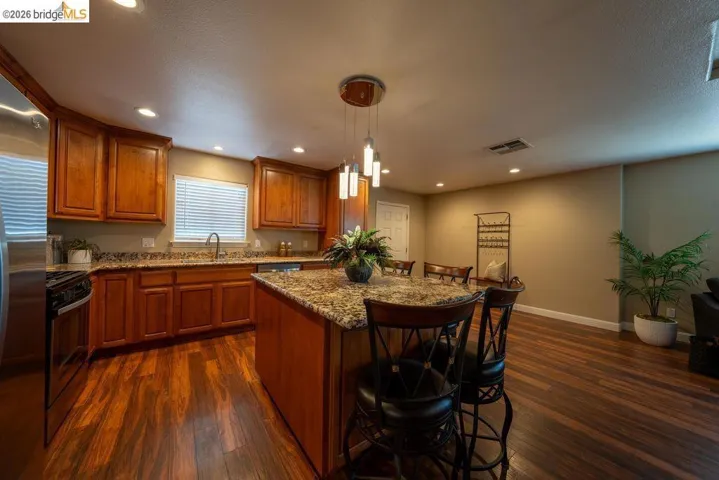 Kitchen featuring wood-finish flooring, recessed lighting, and a center island with a granite-style countertop