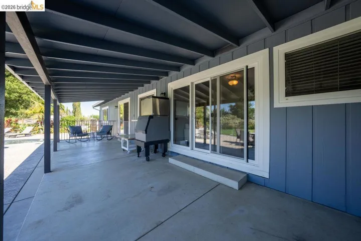 Expansive concrete patio beneath a dark-painted exposed beam ceiling