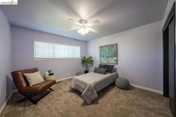 Spacious room with light lavender walls, plush carpet, and a ceiling fan with integrated lighting
