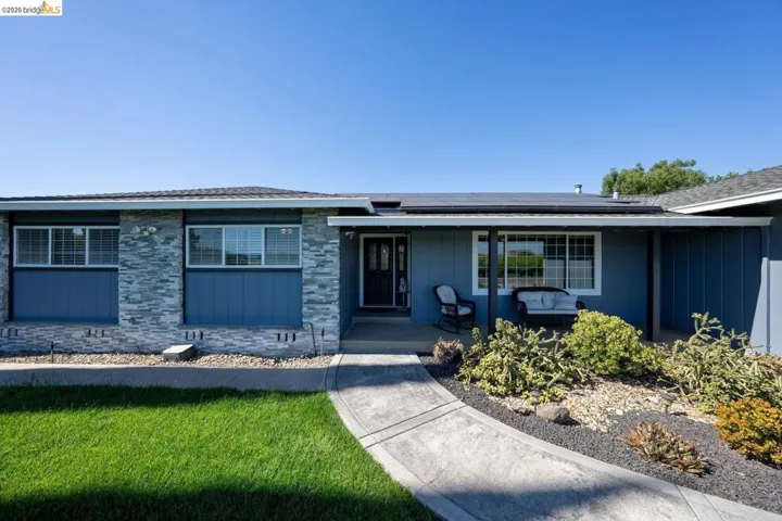 Single-story residence featuring a blue exterior, stone veneer accents, and multiple windows