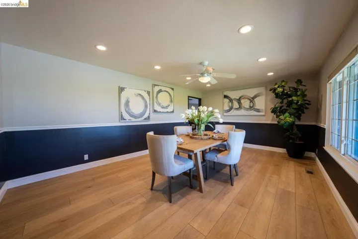 Spacious room featuring wood-finish flooring and a two-tone wall treatment with white wainscoting