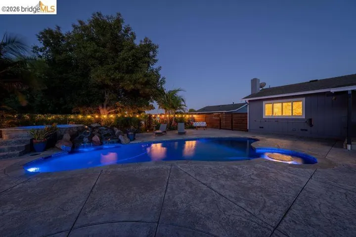 Curved swimming pool with integrated spa and rock waterfall feature