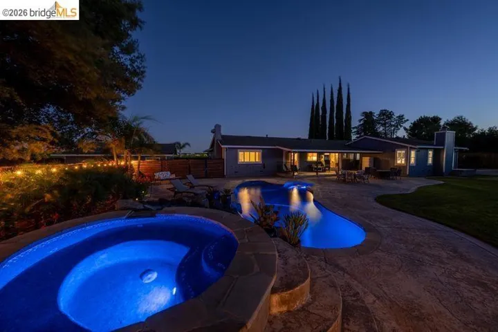 Outdoor spa and swimming pool with stone surround and stamped concrete patio
