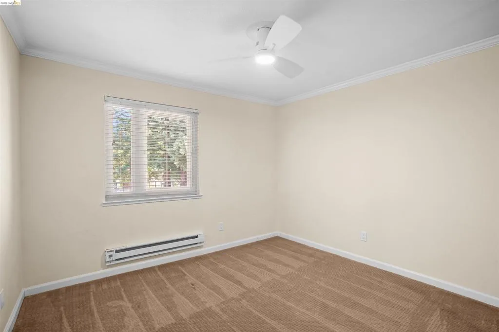 Room featuring neutral wall tones, crown molding, and a ceiling fan with integrated lighting