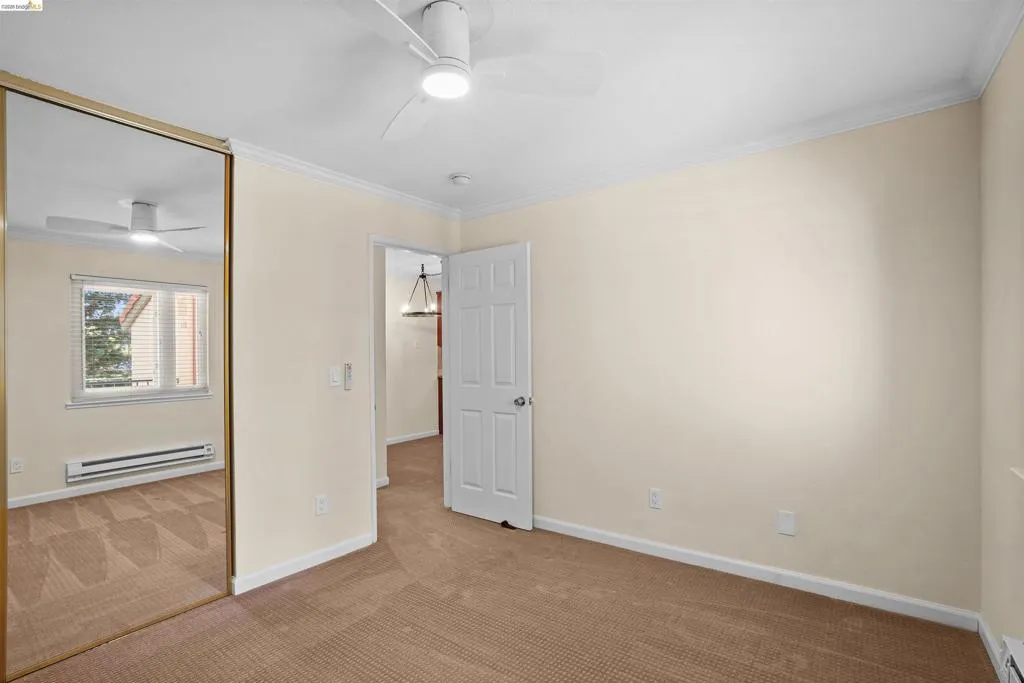 Bedroom featuring warm-toned carpet flooring, a ceiling fan with integrated lighting, and crown molding