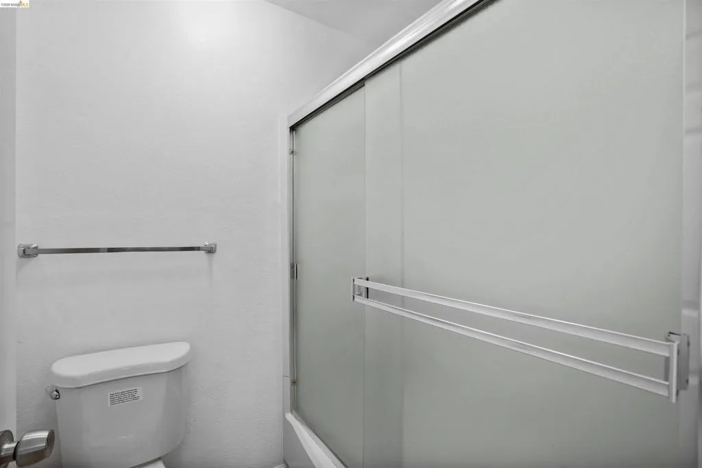 Bathroom featuring a white toilet, chrome towel bar, and a shower enclosure with frosted sliding glass doors