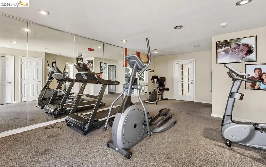 Dedicated fitness area featuring carpet flooring and mirrored wall panels