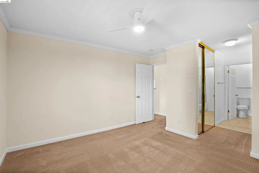 Carpeted bedroom with crown molding, a ceiling fan with integrated lighting, and a mirrored closet