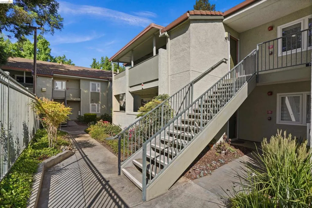 Exterior building featuring stucco siding, multiple windows, and a prominent outdoor staircase with metal railings