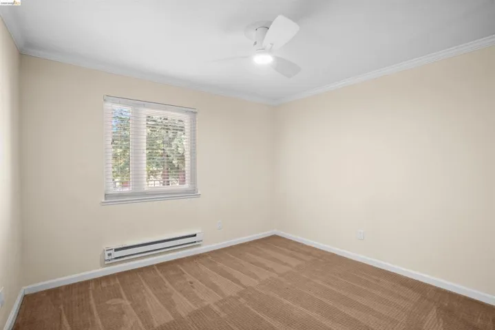Room featuring neutral wall tones, crown molding, and a ceiling fan with integrated lighting