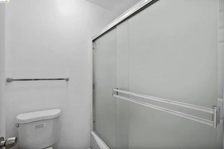 Bathroom featuring a white toilet, chrome towel bar, and a shower enclosure with frosted sliding glass doors