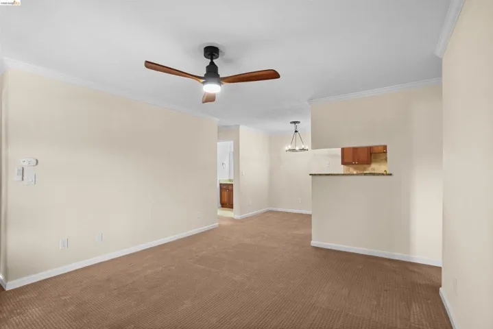Carpeted living area featuring a ceiling fan with integrated lighting