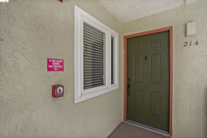 Entryway featuring a paneled door with contrasting trim, adjacent window with blinds, and stucco exterior