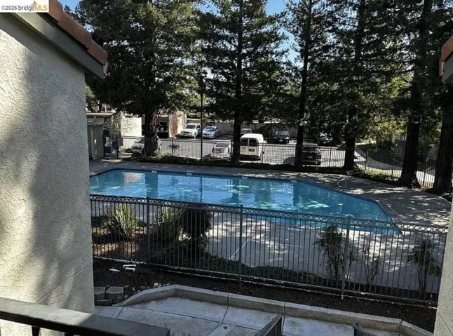Rectangular swimming pool with a black wrought iron fence