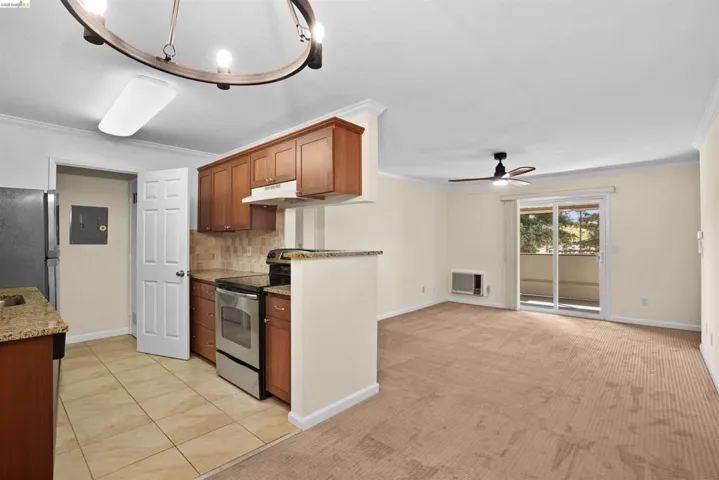 Open-concept living space featuring a kitchen with wood cabinetry, stainless steel appliances, and a tiled backsplash
