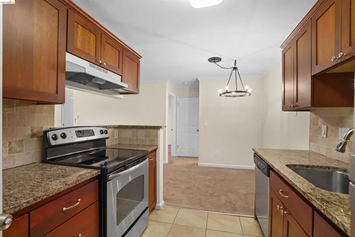 Kitchen featuring wood cabinetry, stainless steel appliances, granite countertops, and a tiled backsplash