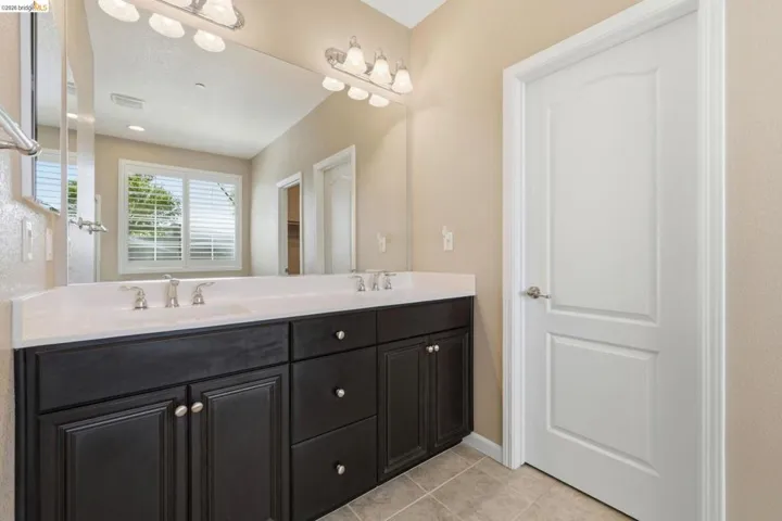 Double vanity featuring dark wood cabinetry, white countertops, and brushed nickel fixtures