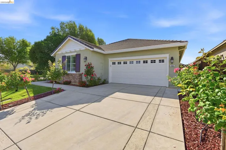 Single-story residence featuring stucco siding, a tiled roof, and a two-car garage with a panel door and upper window inserts