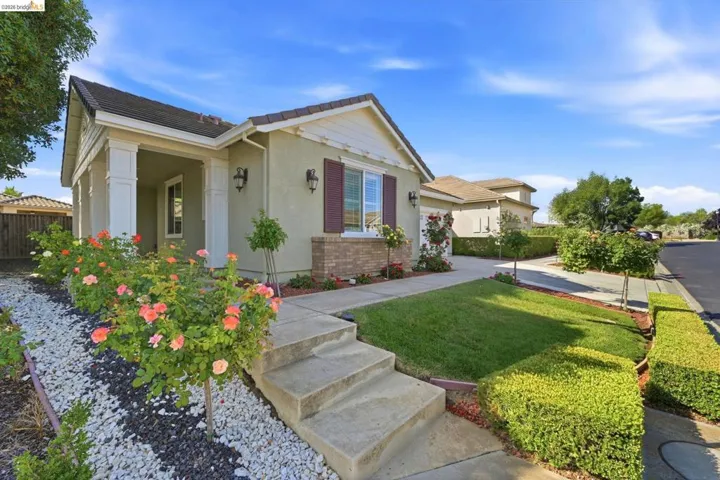 Inviting stucco exterior with a tiled roof, featuring a covered porch entry with decorative columns