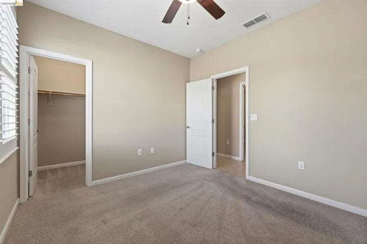 Carpeted room with neutral wall tones and a ceiling fan