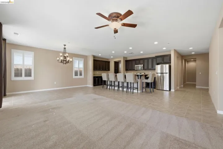 Open-concept living area featuring a kitchen with dark cabinetry, stainless steel appliances, and a breakfast bar