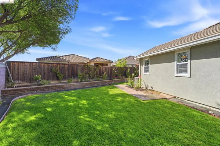 Spacious backyard featuring a manicured lawn, a retaining wall with integrated planters, and a privacy fence