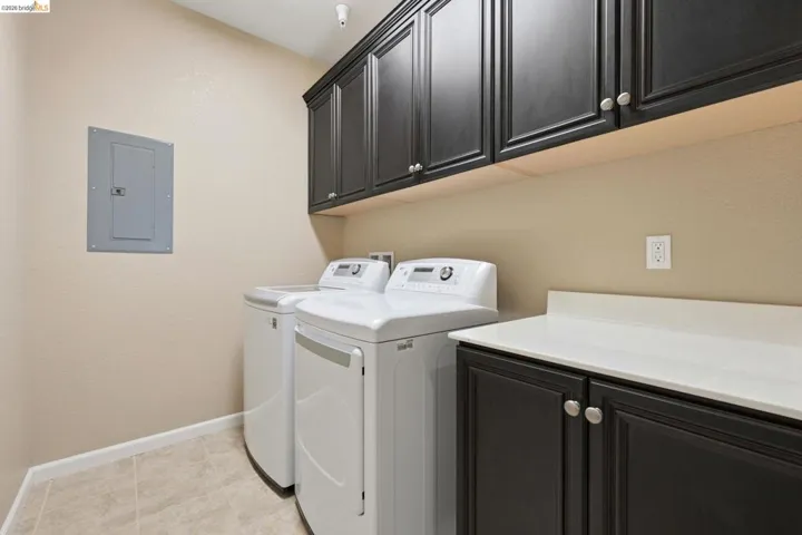 Functional utility room featuring dark wood-finish cabinetry, a light-toned countertop, and durable tile​​‌​​​​‌​​‌‌​​‌​​​‌‌​​​‌​​‌‌​​‌‌​​‌‌​​​​ flooring
