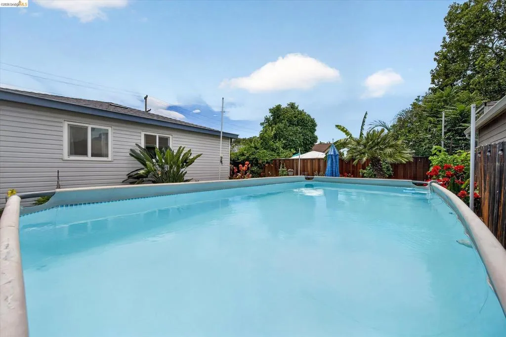 Backyard featuring an above-ground swimming pool, wood fencing, and mature landscaping