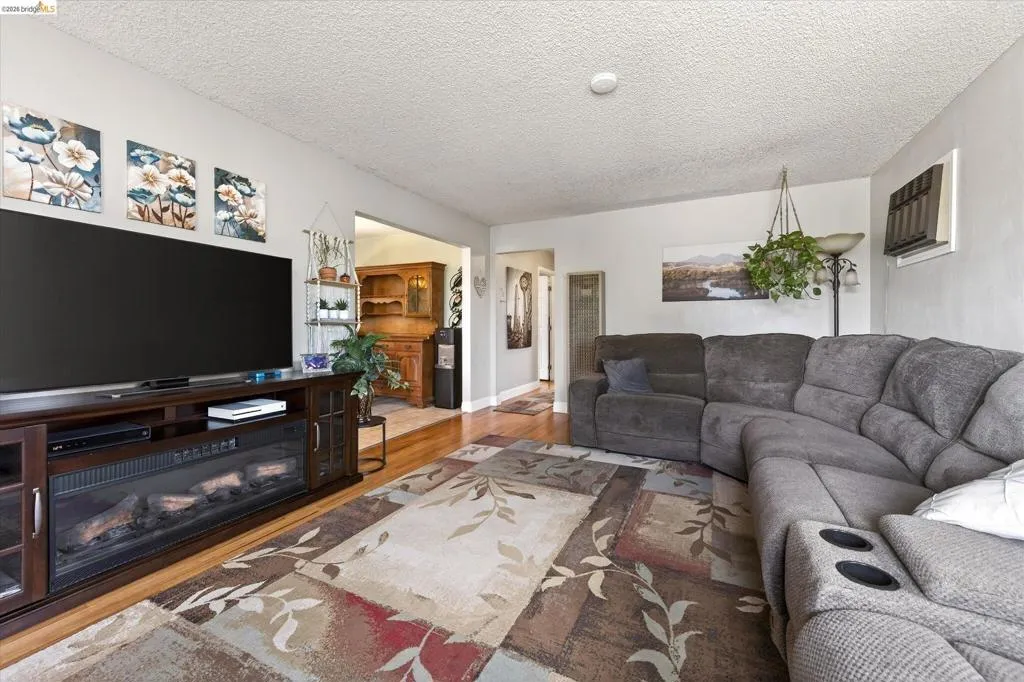 Bright living area featuring wood-finish flooring, light gray wall paint, and a textured white ceiling