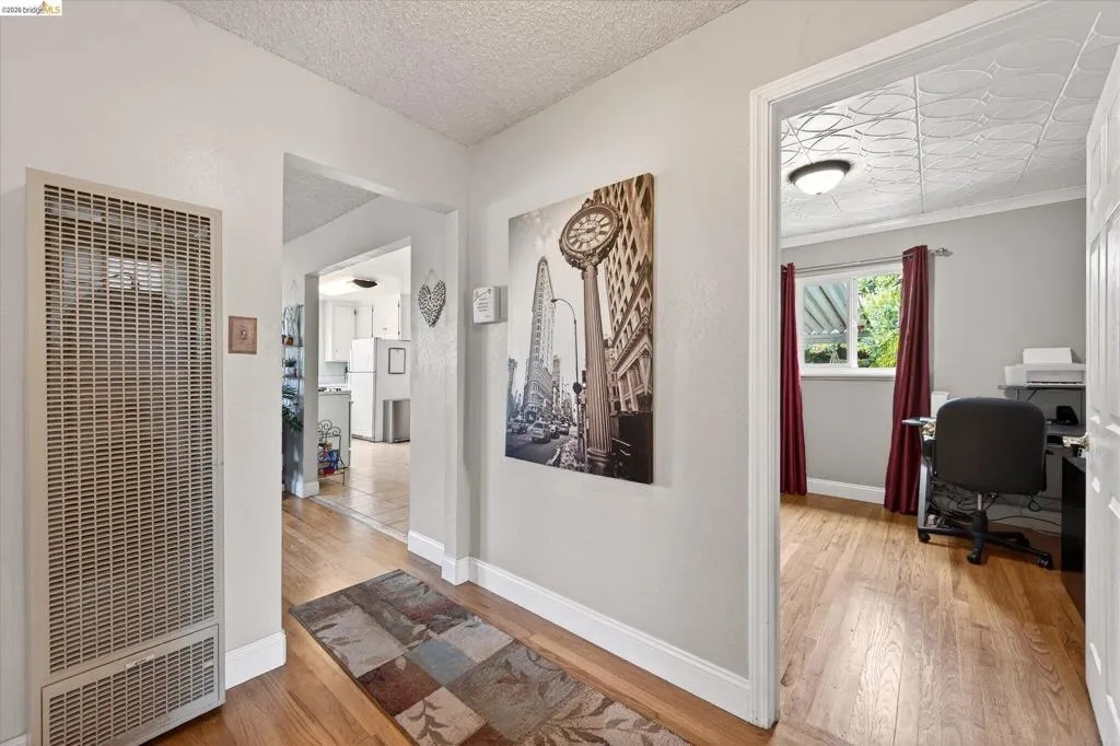 Hallway featuring wood-finish flooring, white baseboards, and a wall-mounted heater