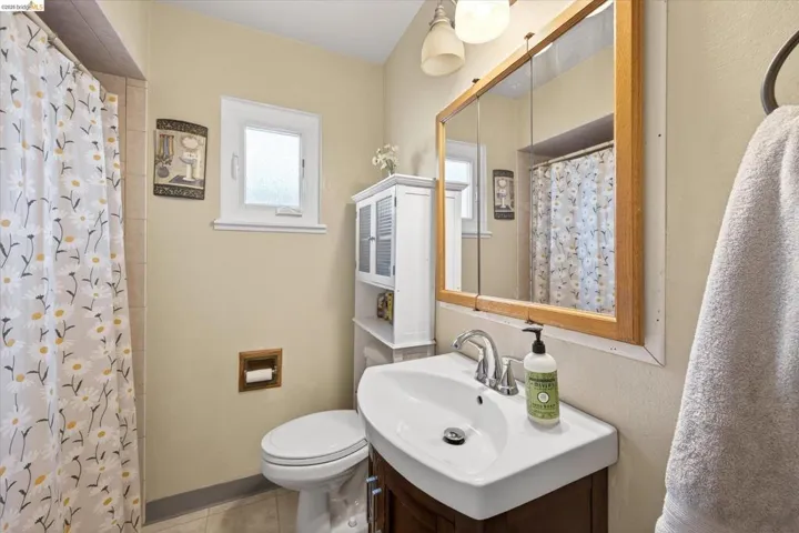 Bathroom featuring a wood-finish vanity with a white rectangular sink, framed medicine cabinet, and built-in shelving unit