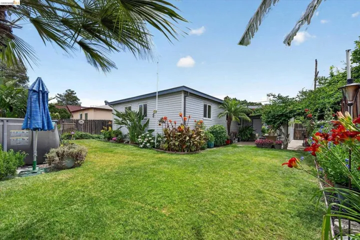 Expansive green lawn surrounded by mature landscaping and vibrant floral beds