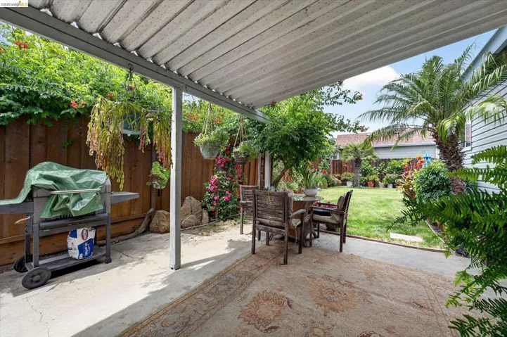 Covered patio area with concrete flooring, featuring a slatted patio cover