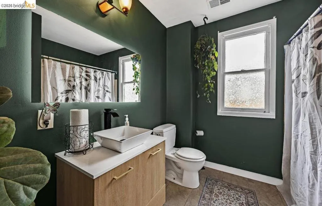 Bathroom featuring a wood-finish vanity with a white countertop and a vessel sink