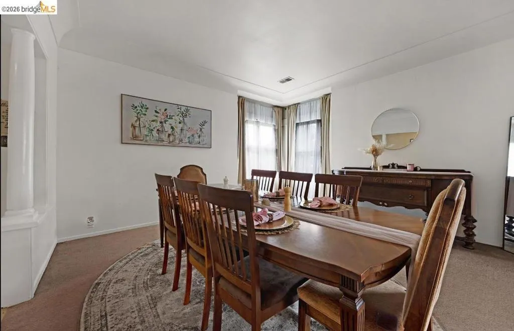 Spacious dining area featuring white walls, carpet flooring, a decorative archway, and crown molding