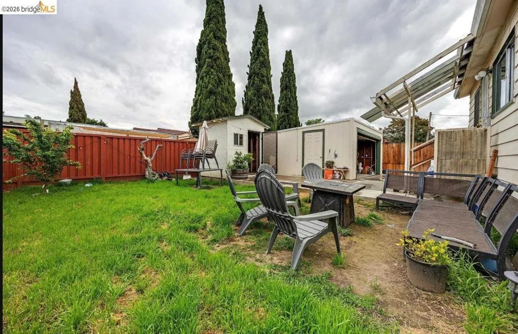 Expansive backyard featuring a lush lawn, privacy fencing, and mature vertical landscaping