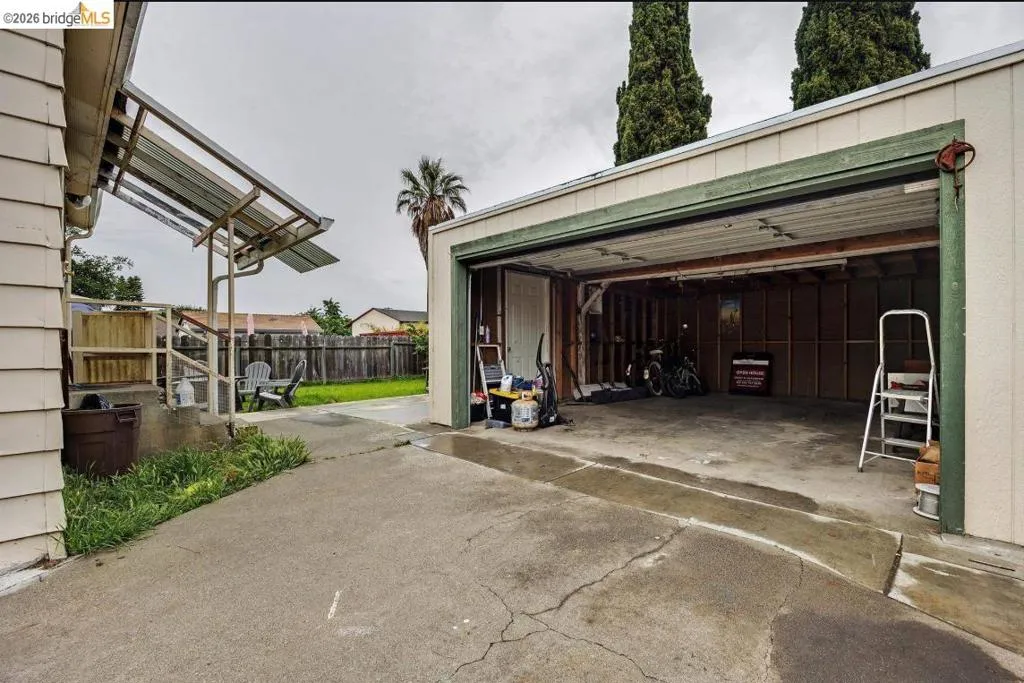 Spacious two-car garage with an open door revealing interior framing and concrete flooring