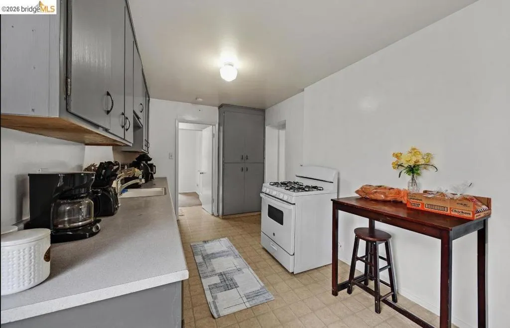 Functional kitchen featuring a white gas range, ample gray cabinetry, and light-colored countertops